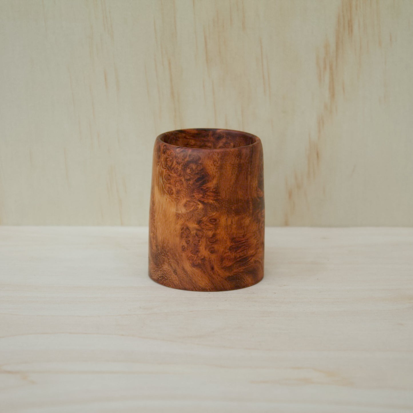 Wooden vase on a wooden surface with a light wood background