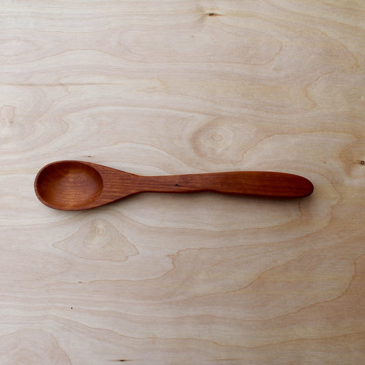 hand made wooden spatula, made with cherry wood, on a light wooden background