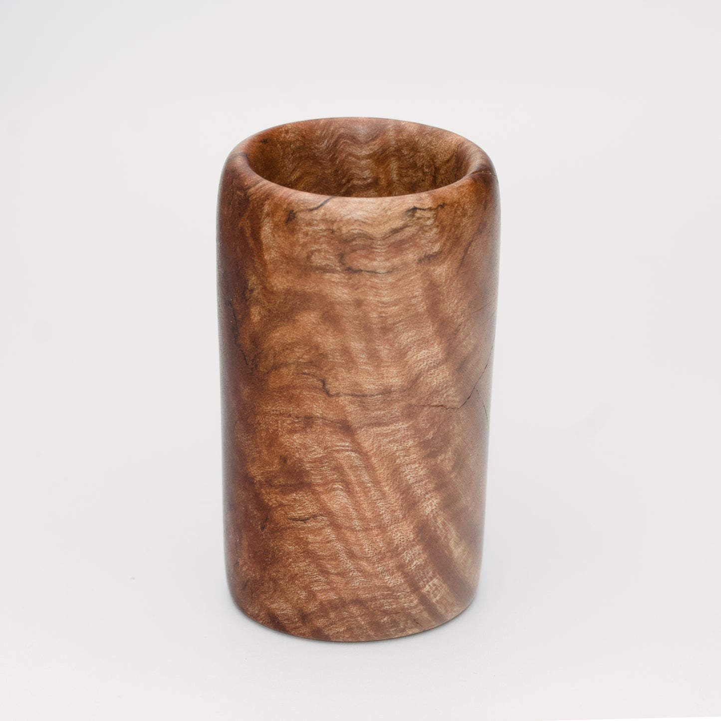 Figured maple wood shot glass against white background