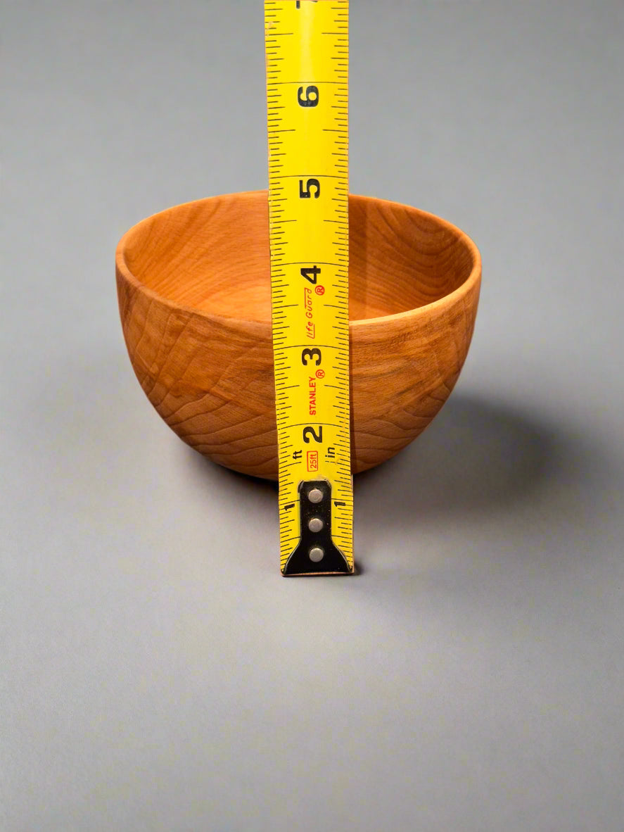 Wooden bowl with a measuring tape on a gray surface