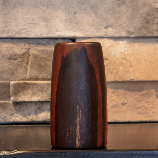 The First Lesson Eastern Redbud shot glass with dark central figure framed by reddish-brown grain
