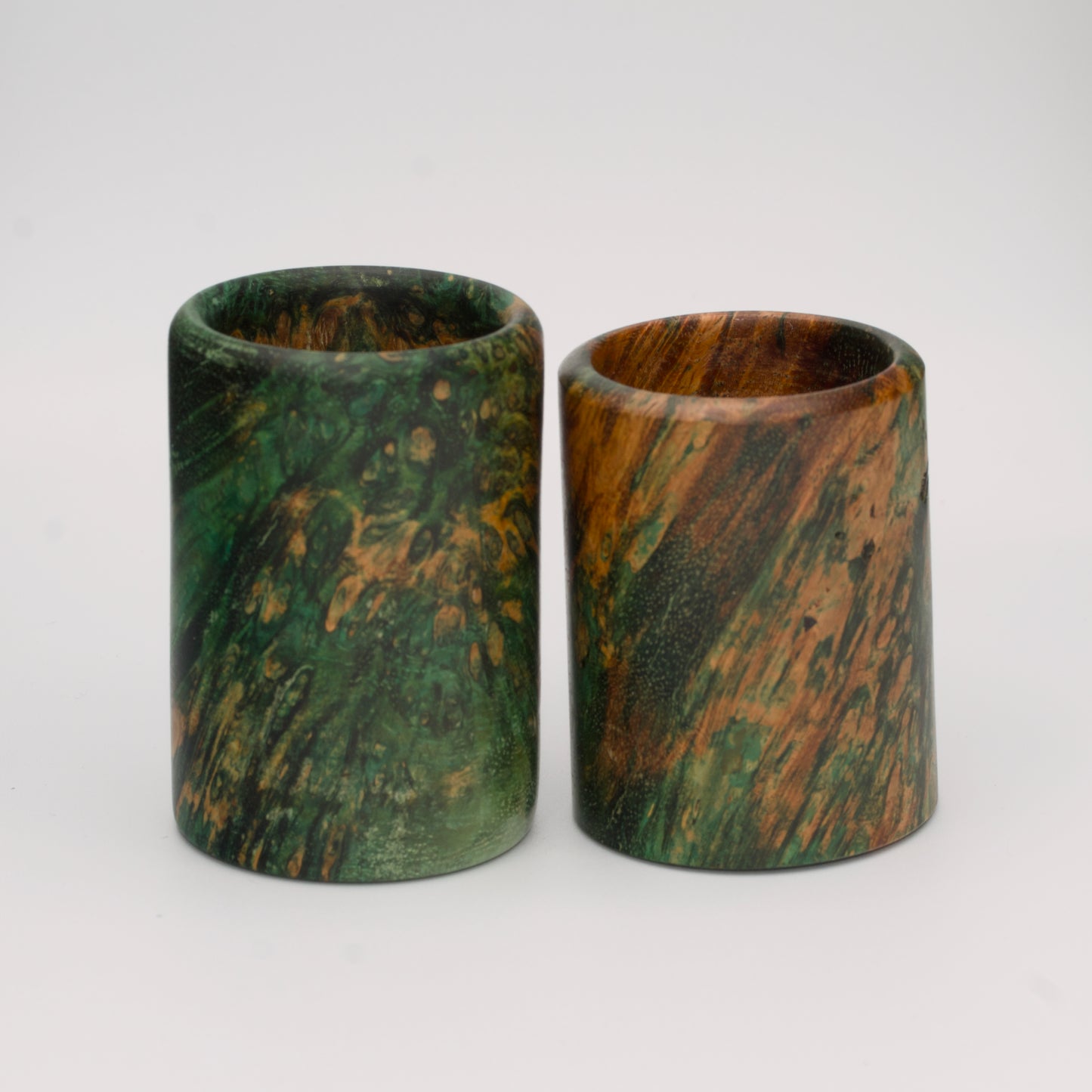 Pair of dyed green river tamarind burl shot glasses against white background