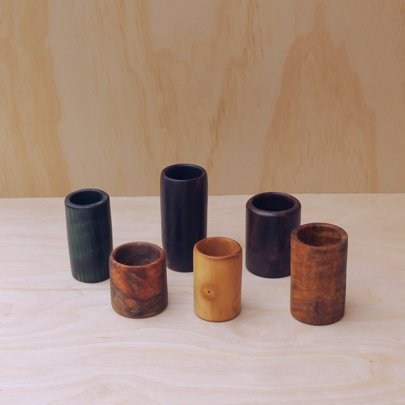 colorful, hand crafted wooden shot glasses, espresso cups on a light wooden background