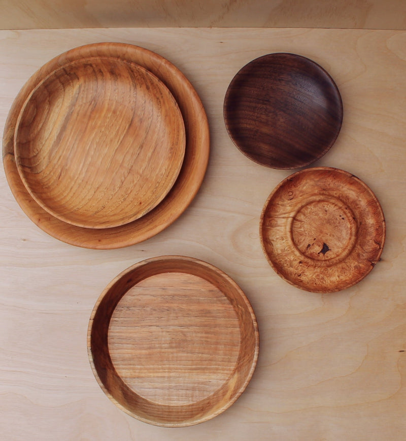 variety of colors of hand made wooden plates and decorative plates for home decor on a light wooden background