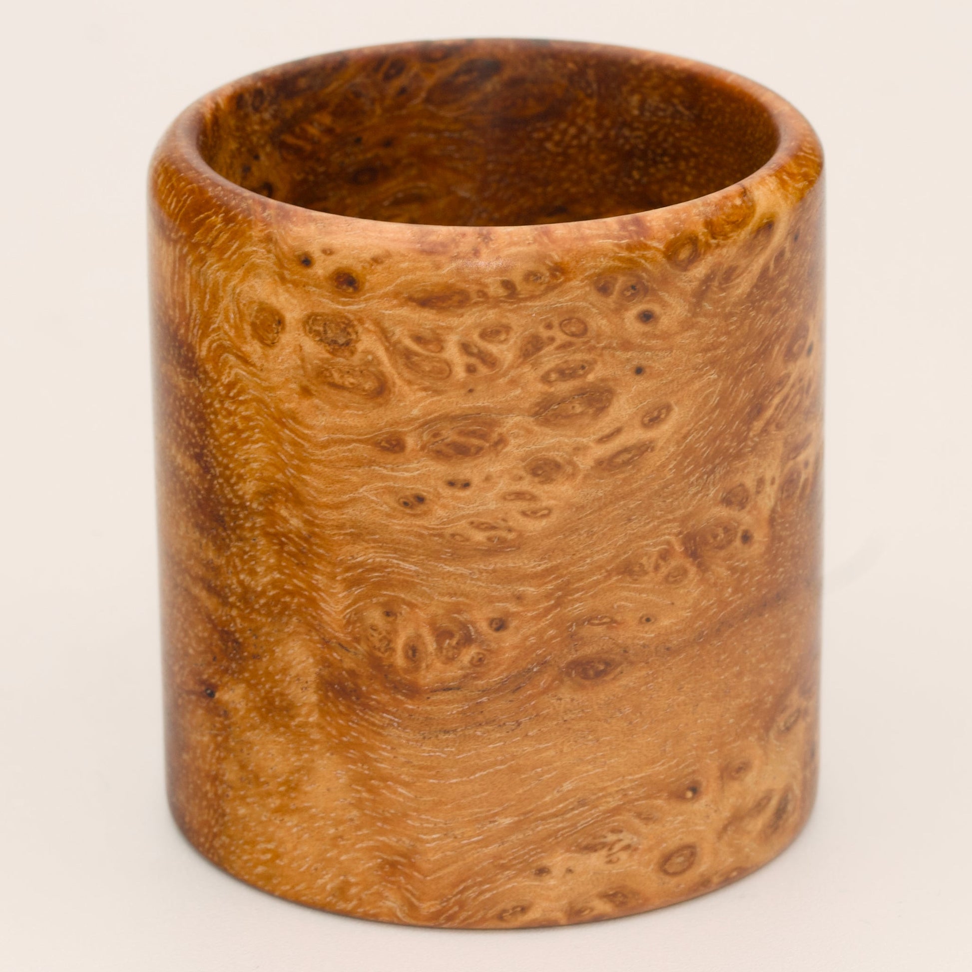 Amber colored River Tamarind Burl wood shot glass on white background