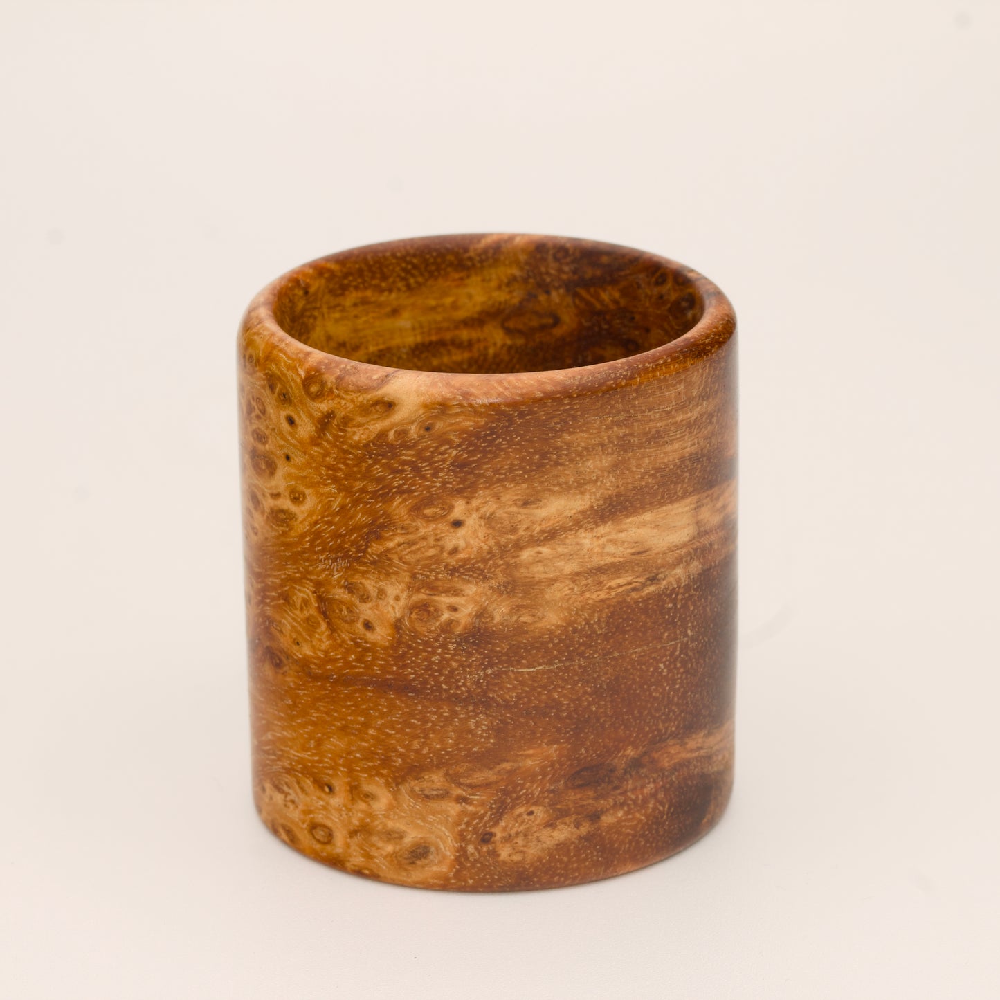 Amber colored River Tamarind Burl wood shot glass on white background