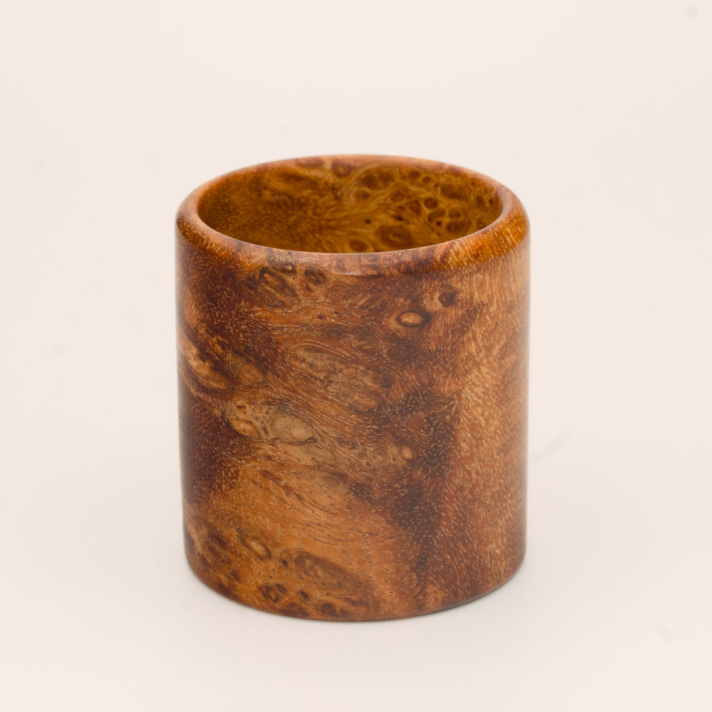 Amber colored River Tamarind Burl wood shot glass on white background
