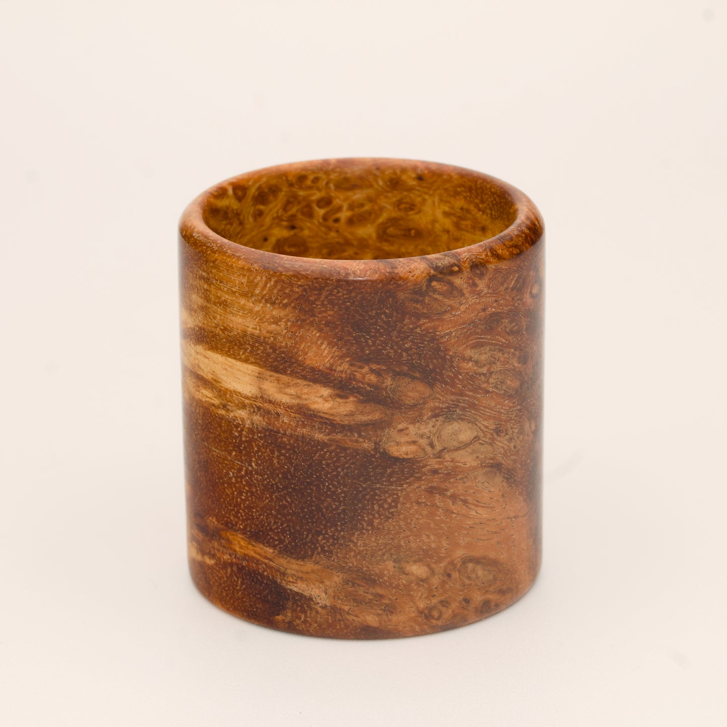 Amber colored River Tamarind Burl wood shot glass on white background