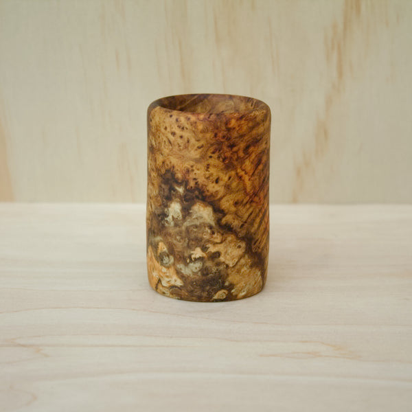 hand made wooden shot glass with rich reddish‑brown tones accented by golden streaks and intricate burl swirls