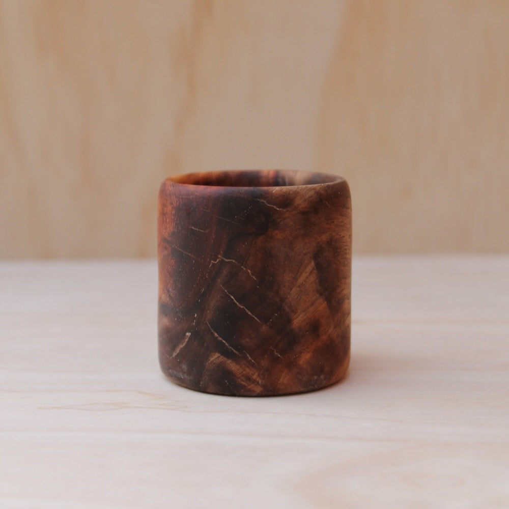 Wooden cup with a marbled pattern on a light wooden surface