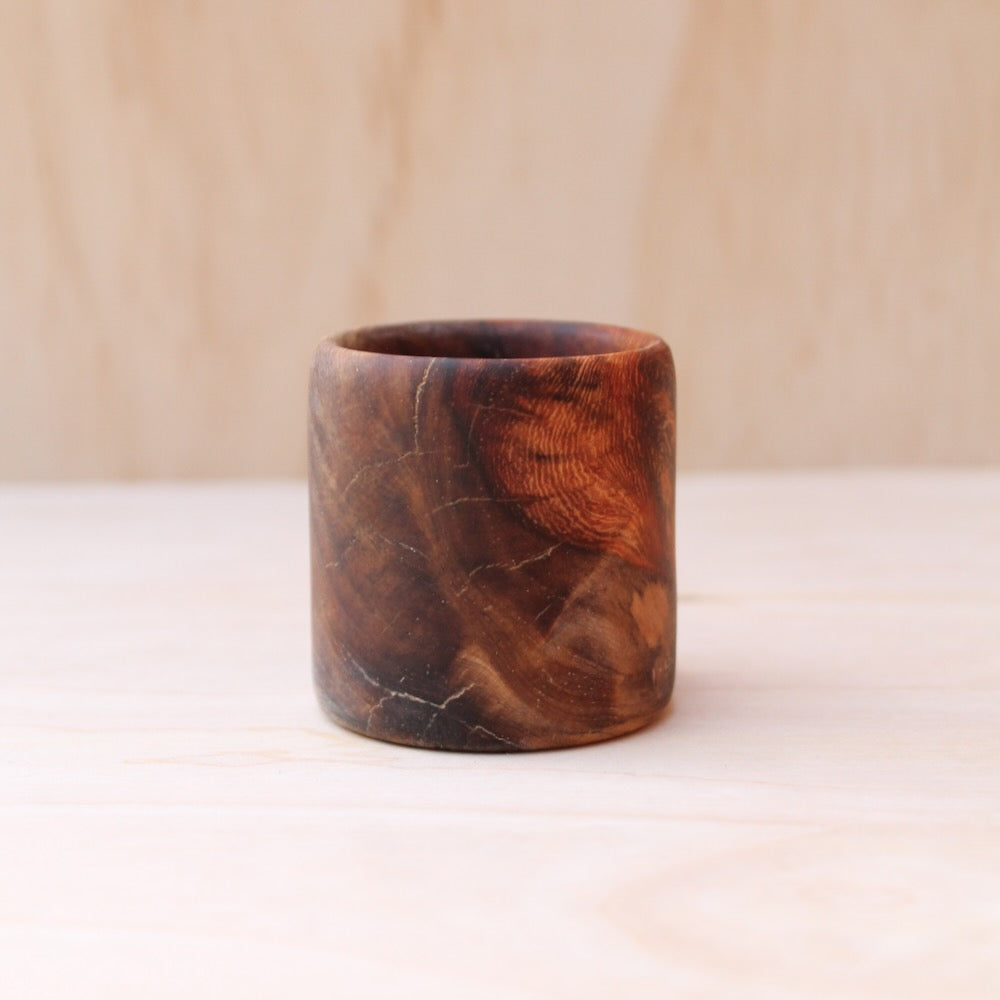 Wooden cup with a natural grain pattern on a beige background