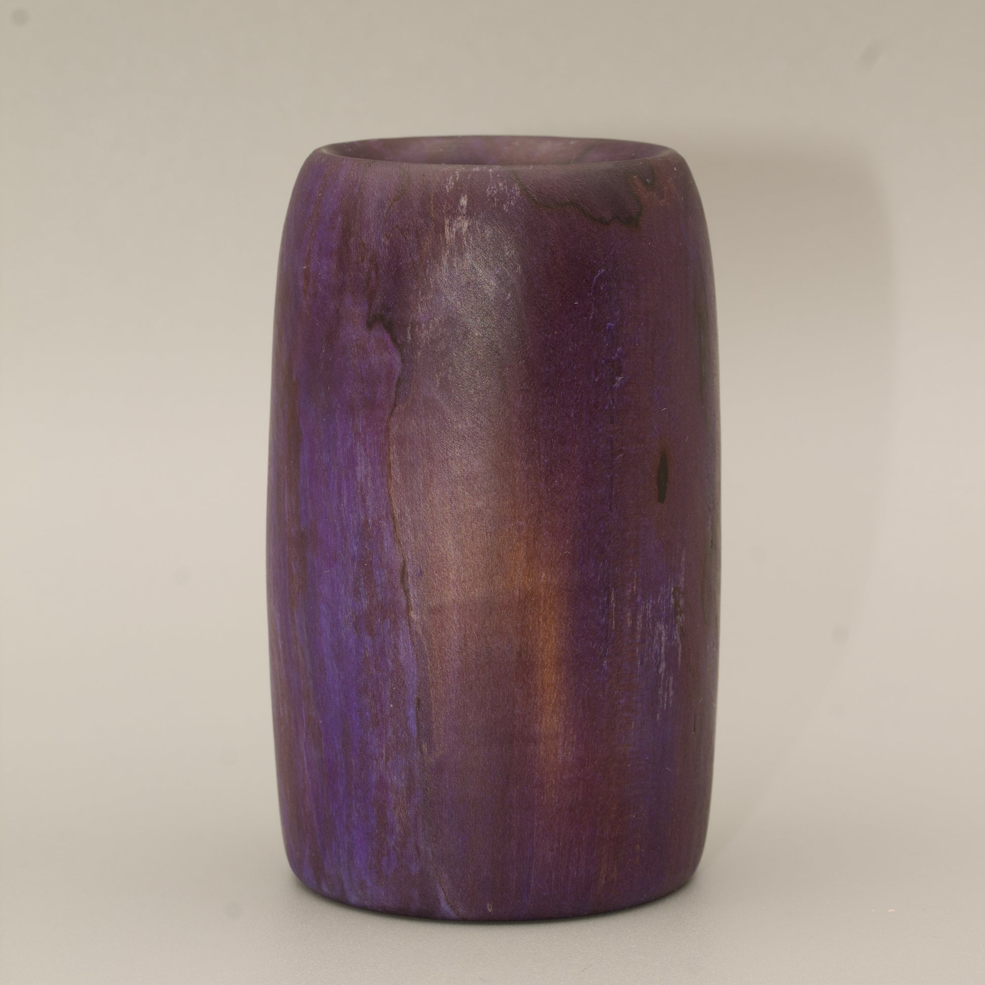 Amethyst colored wood shot glass against white background