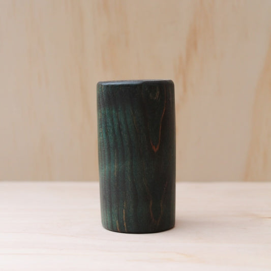 wooden shot glass made of ash wood dyed in blue on a light wood background. The pattern of wood shows hints of light brown
