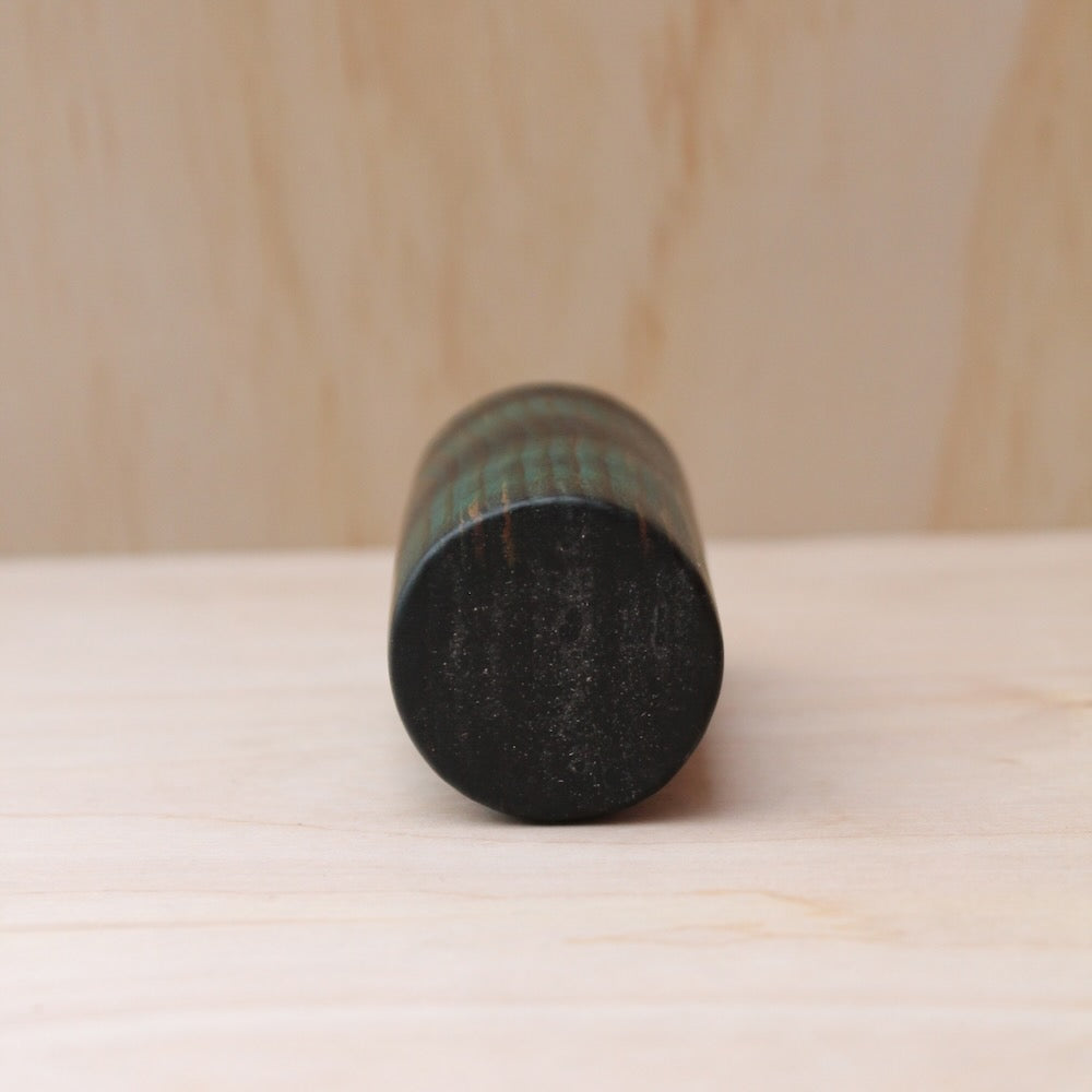 bottom part of a wooden shot glass made of ash wood dyed in blue on a light wood background. 