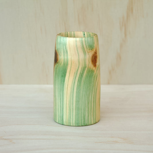 Wooden glass with green and brown striped pattern on a wooden surface