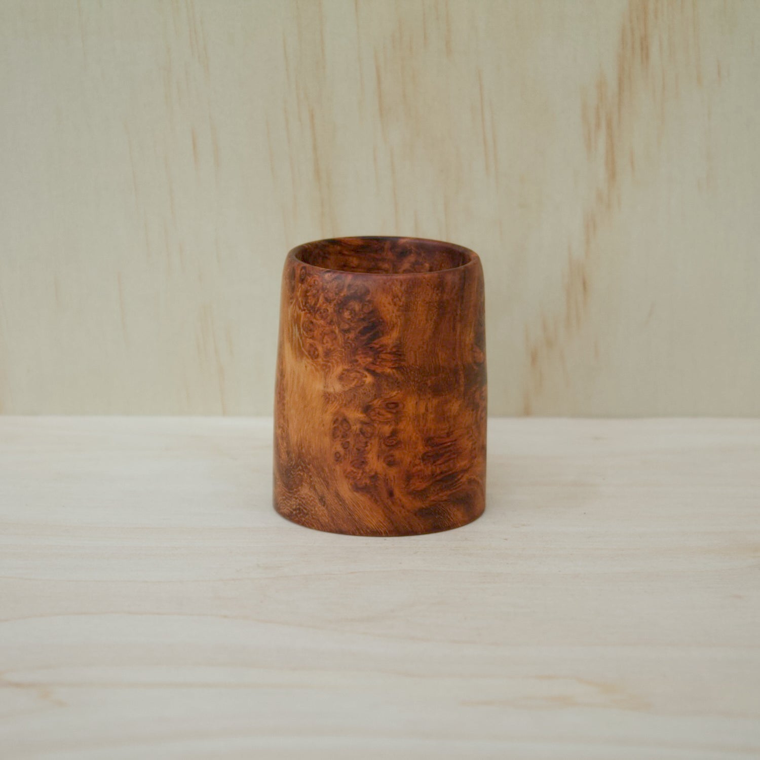 Wooden vase on a wooden surface with a light wood background