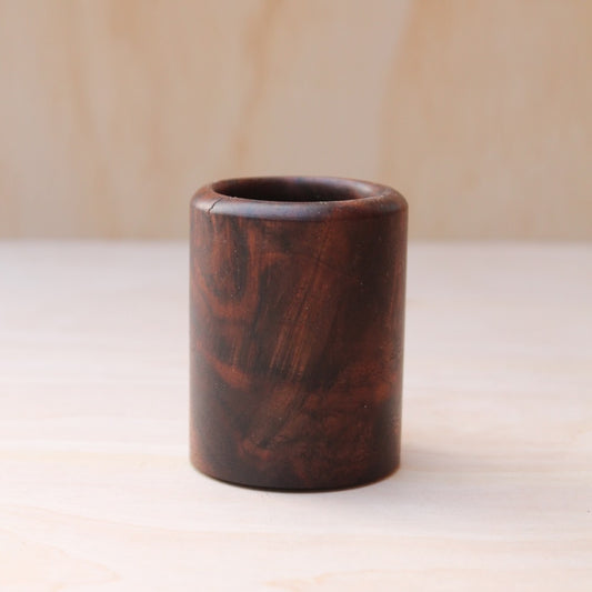 rich brown wooden with lighter streaks and subtle variations in grain shot glass on a light wooden background. 