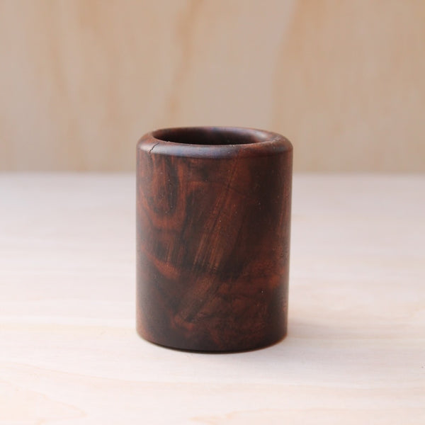 rich brown wooden with lighter streaks and subtle variations in grain shot glass on a light wooden background. 