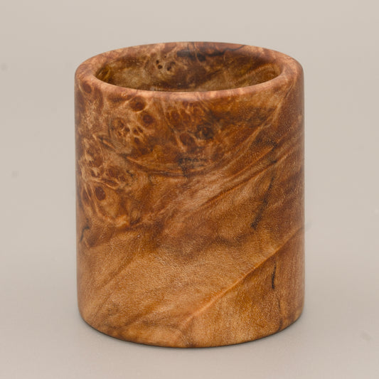 Maple burl end cap shot glass against a grey background