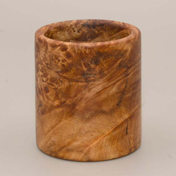 Maple burl end cap shot glass against a grey background