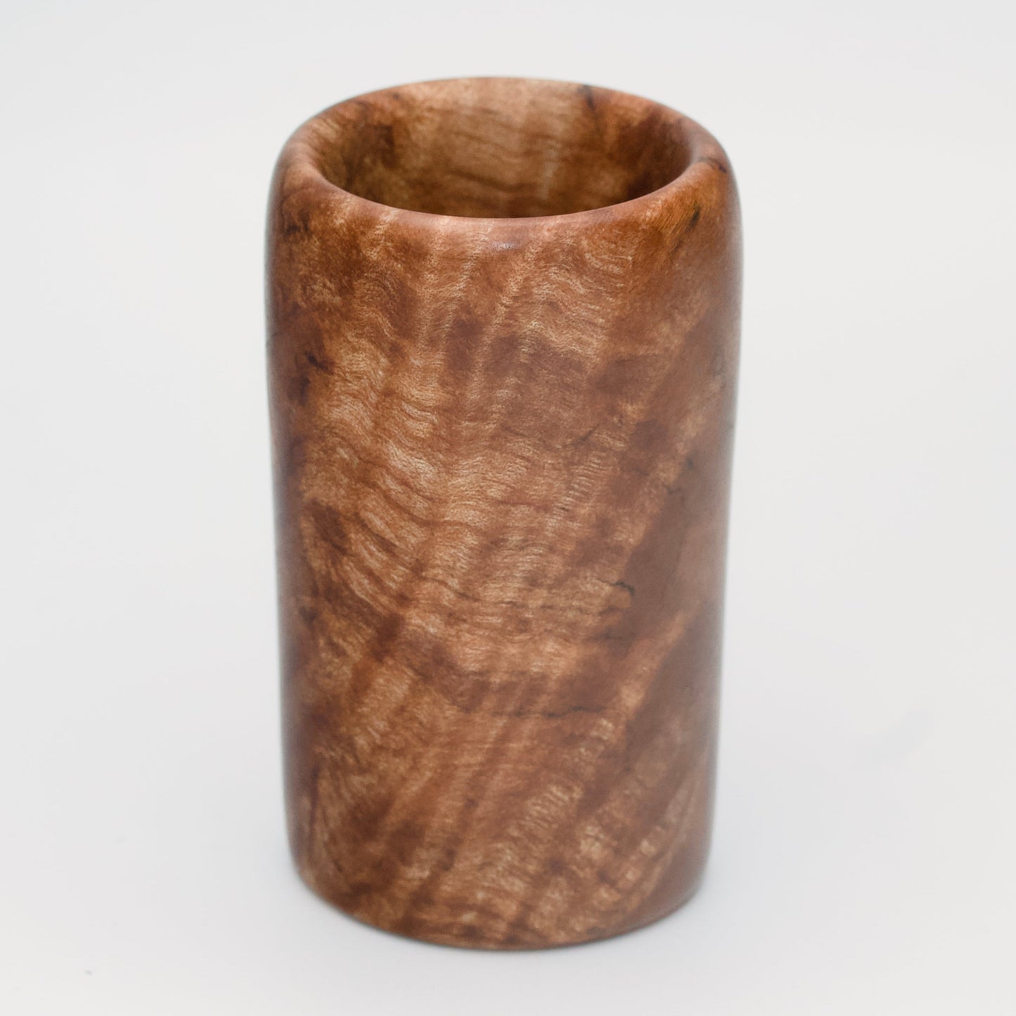 Figured maple wood shot glass against white background