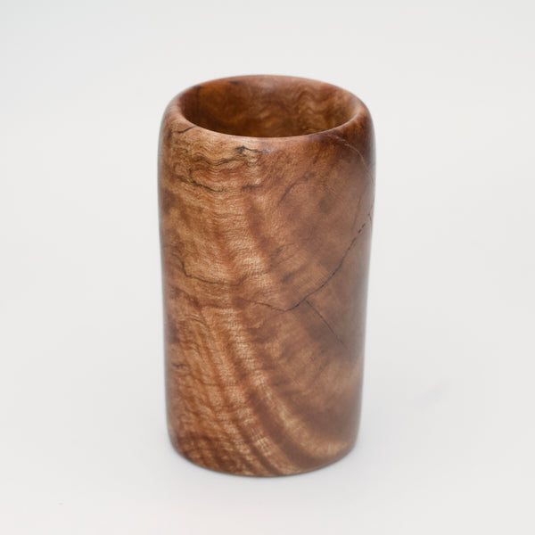 Figured maple wood shot glass against white background