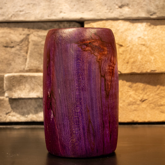 Amethyst colored wood shot glass against stone fireplace background. 