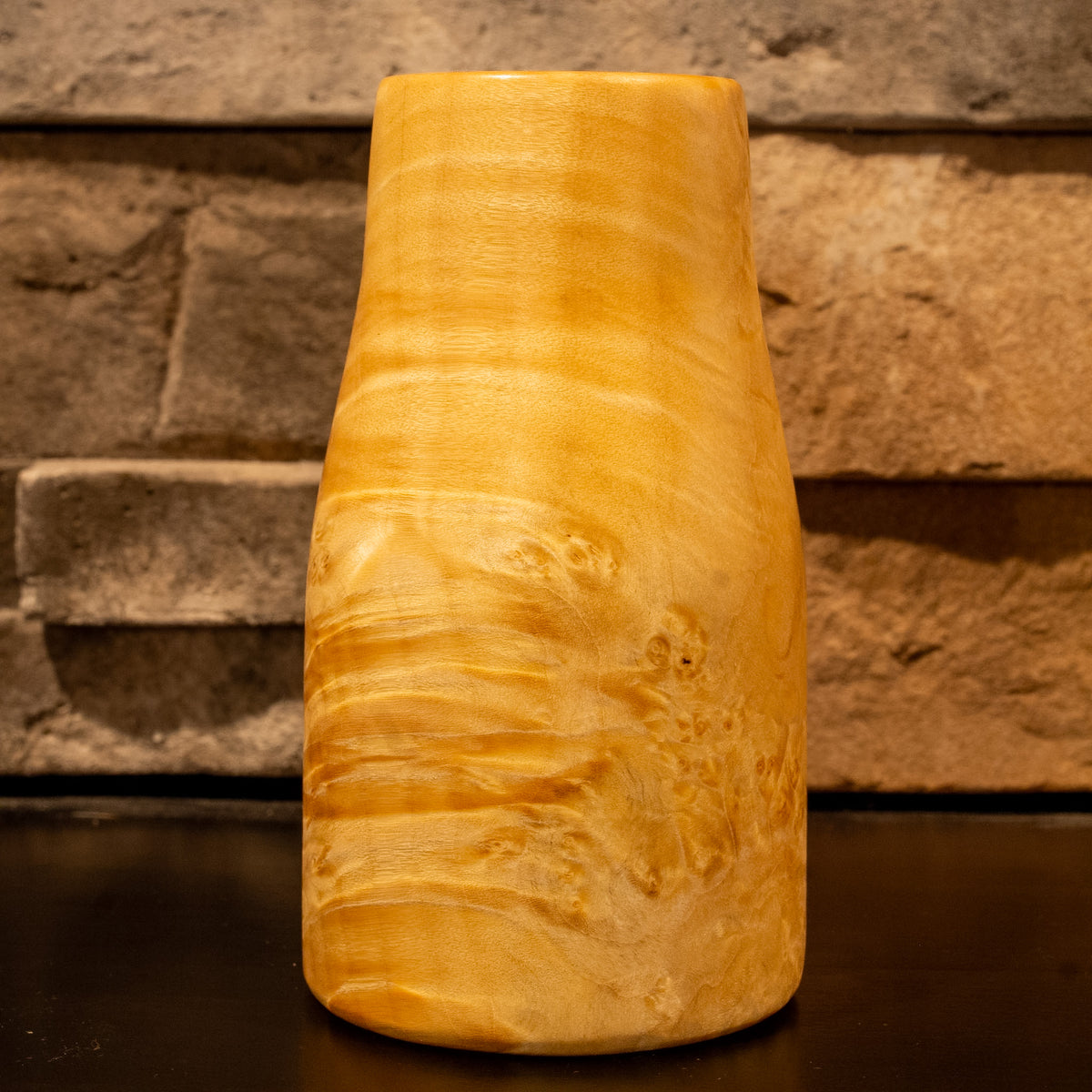 Giant box elder burl wood shot glass against a stone fireplace background