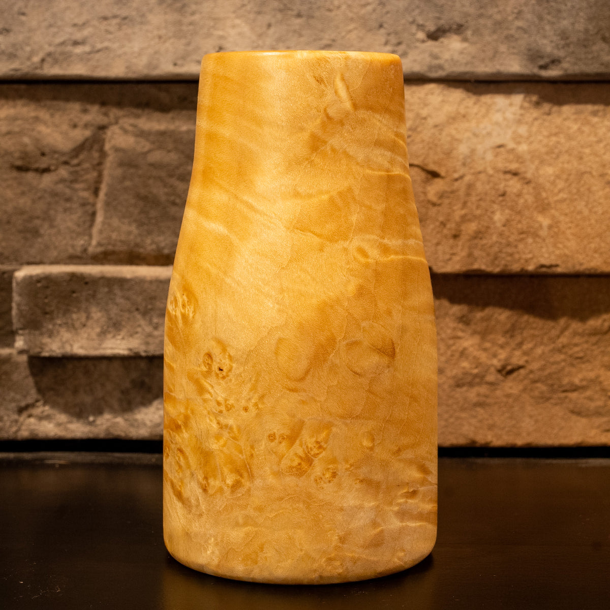 Giant box elder burl wood shot glass against a stone fireplace background