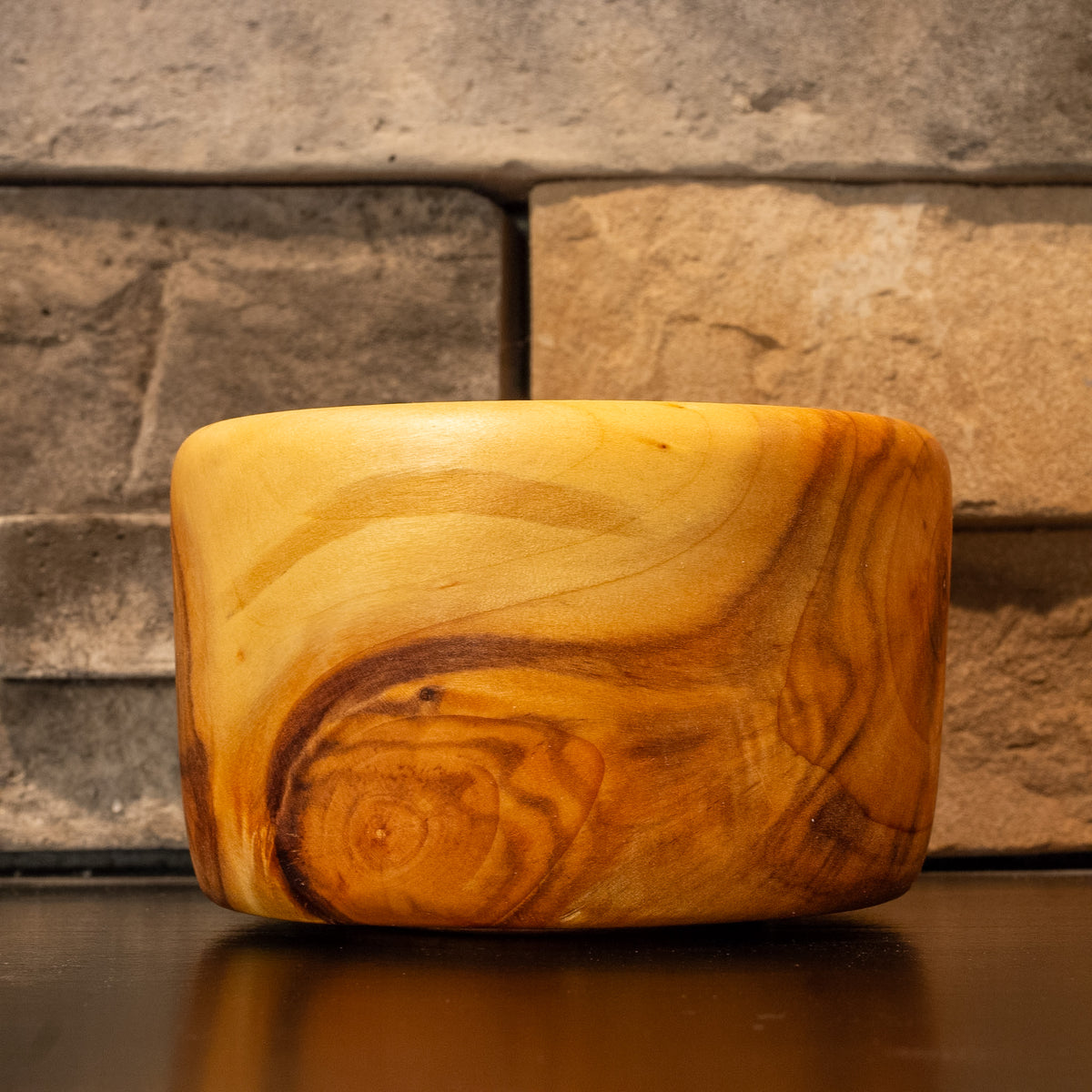 Side profile of The Cherry Creek Plains Cottonwood serving bowl showing a large swirling amber-brown knot figure against pale cream grain
