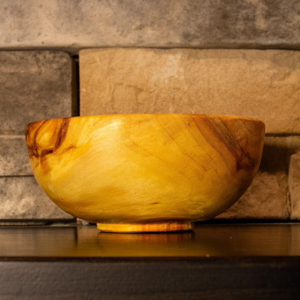 Angled side view of The High Plains Vessel showing golden grain with streaking near the rim and scattered natural marks