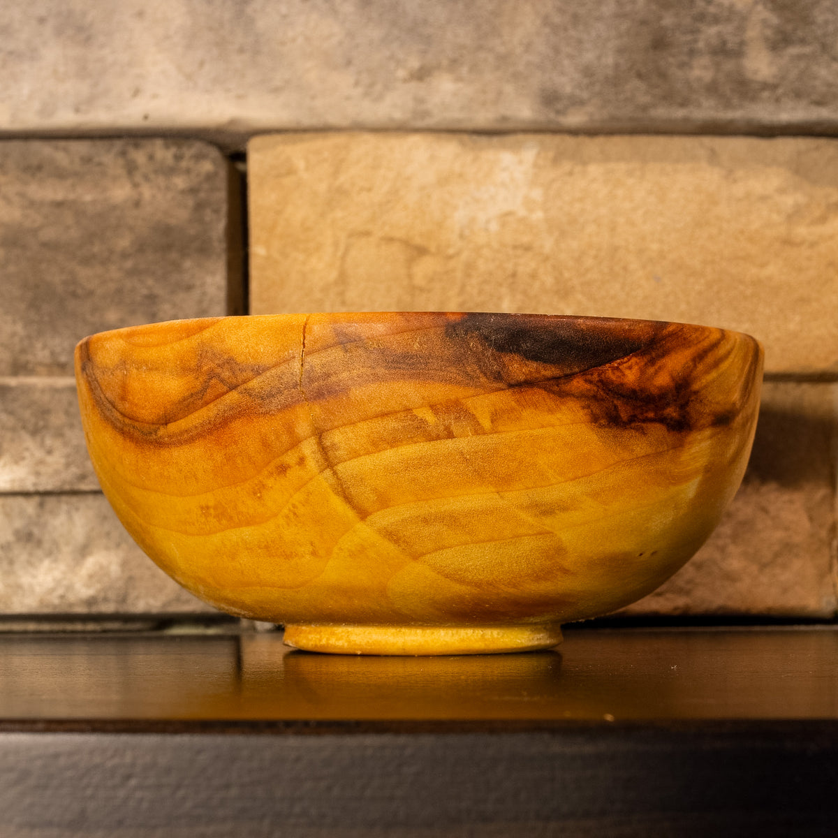 Side view of The High Plains Vessel, a hand-turned Plains Cottonwood bowl, showing a natural crack near the rim and dark mineral streaking across the golden grain