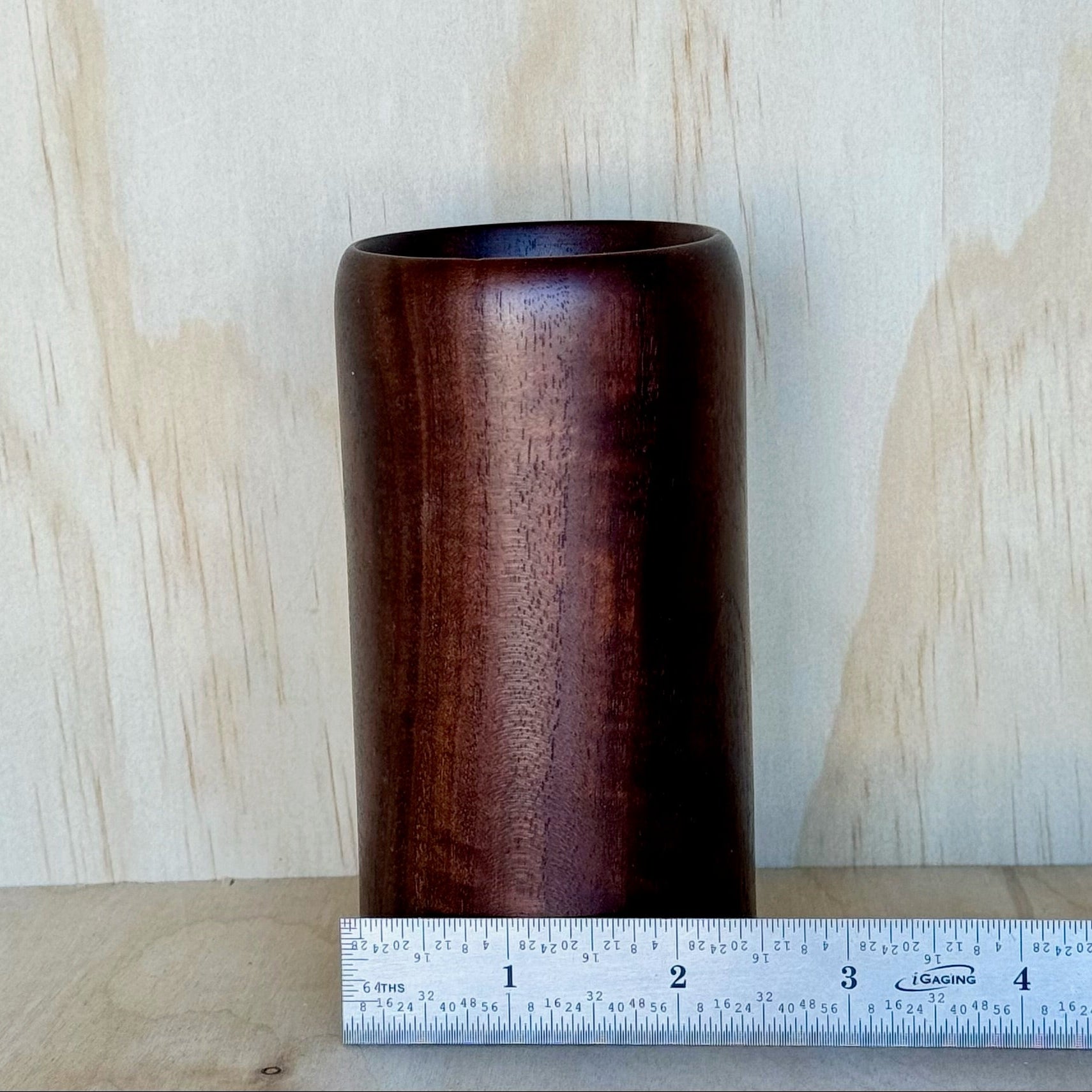 Wooden tumbler on a wooden surface with a light wood panel background and a ruler showing that it is 2-1/2 inches wide