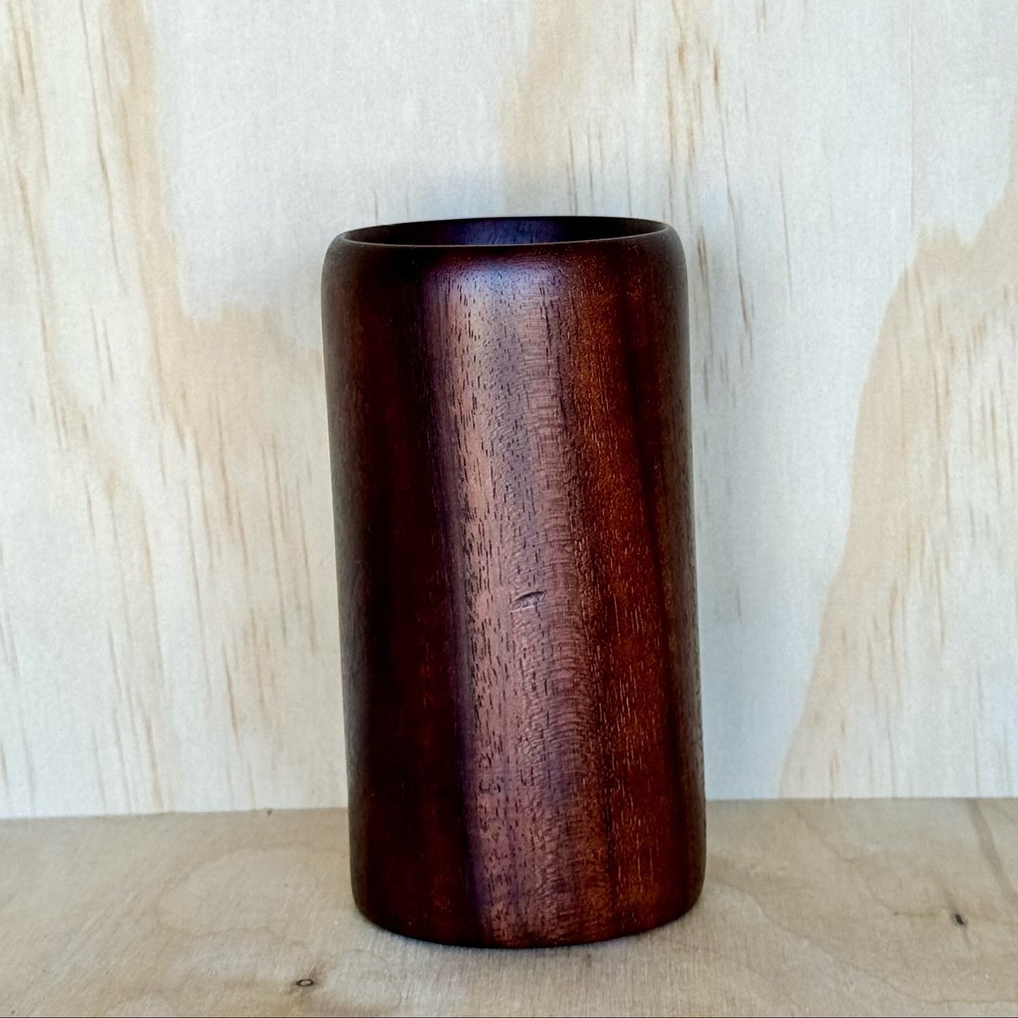 Wooden tumbler on a wooden surface with a light wood panel background