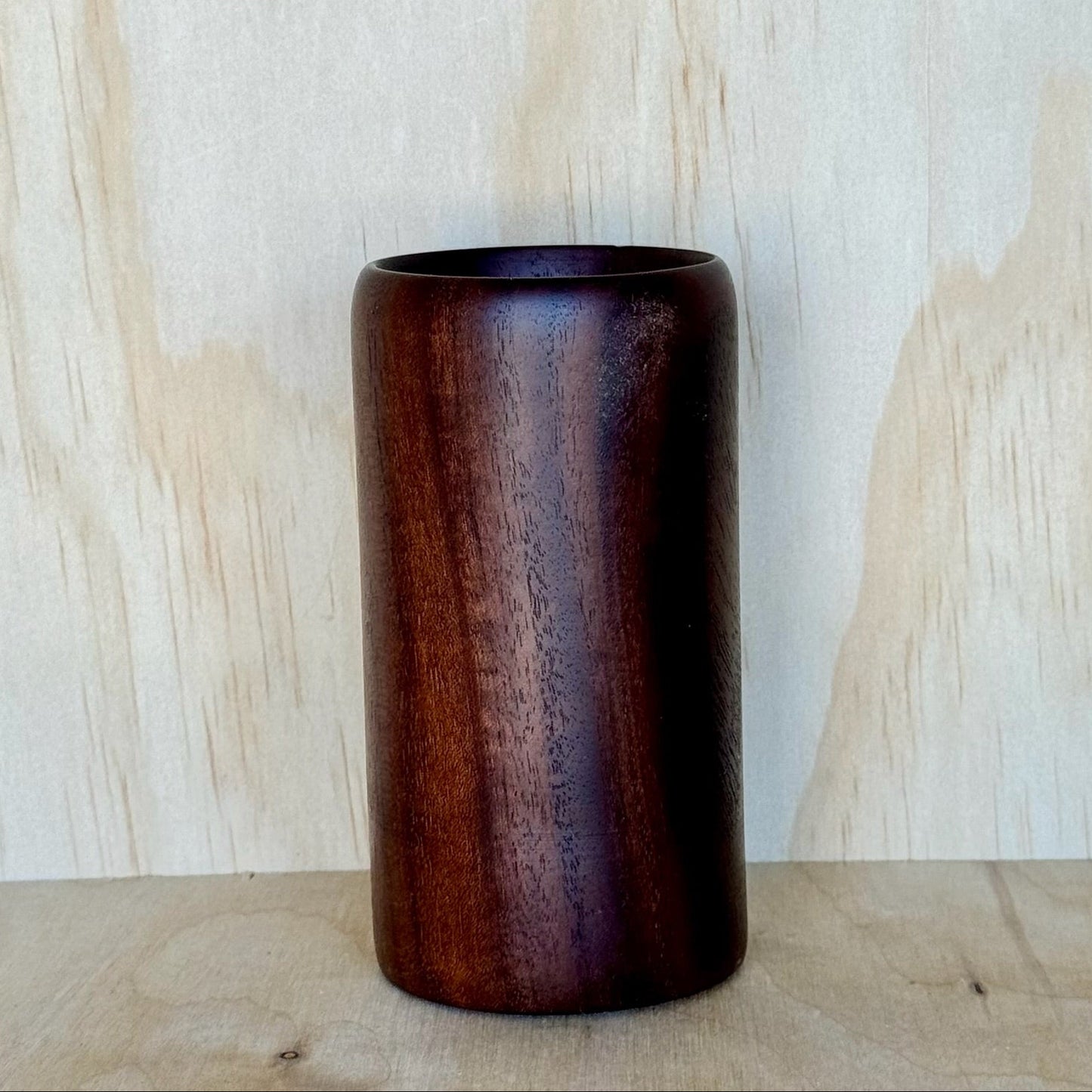 Wooden tumbler on a wooden surface with a light wood panel background