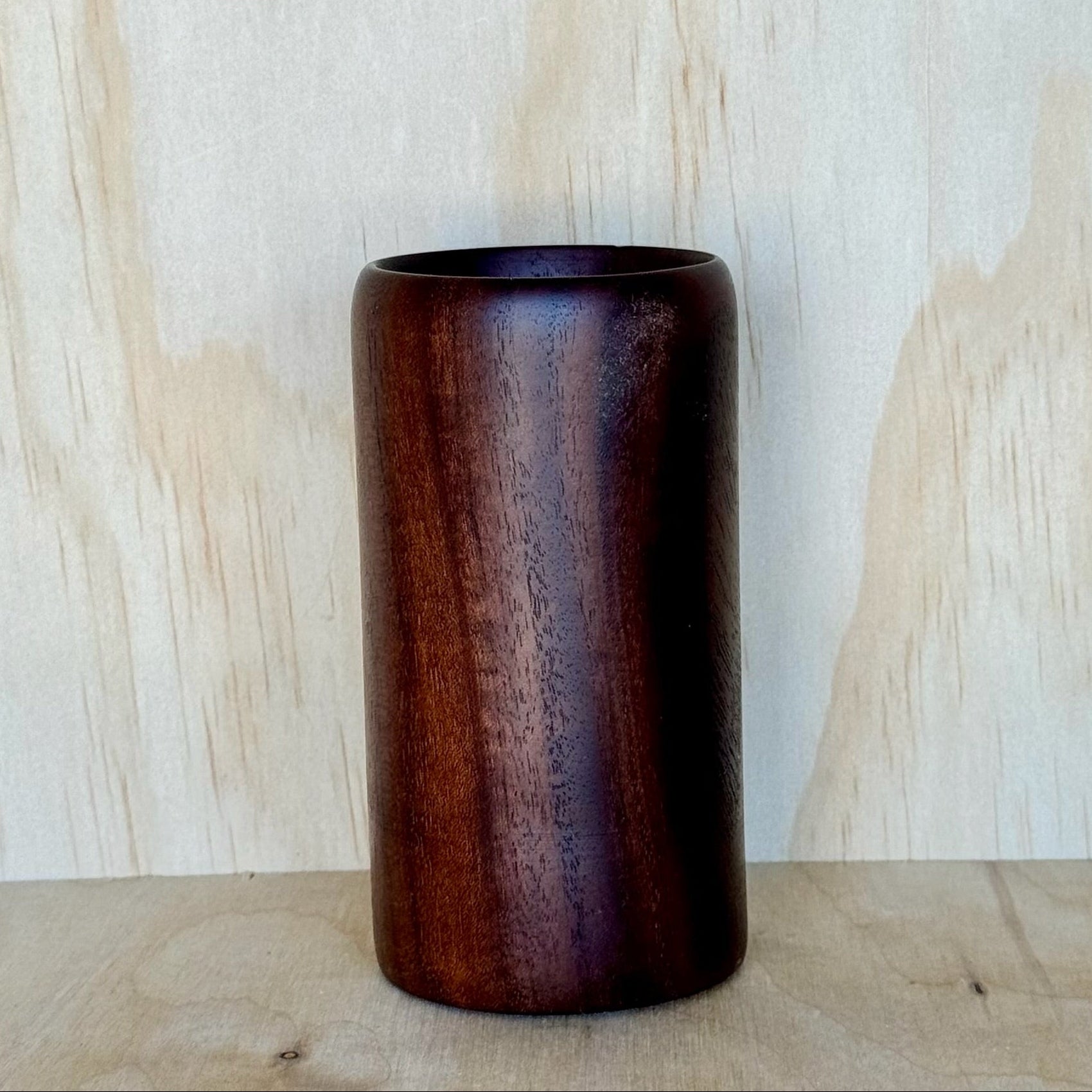 Wooden tumbler on a wooden surface with a light wood panel background