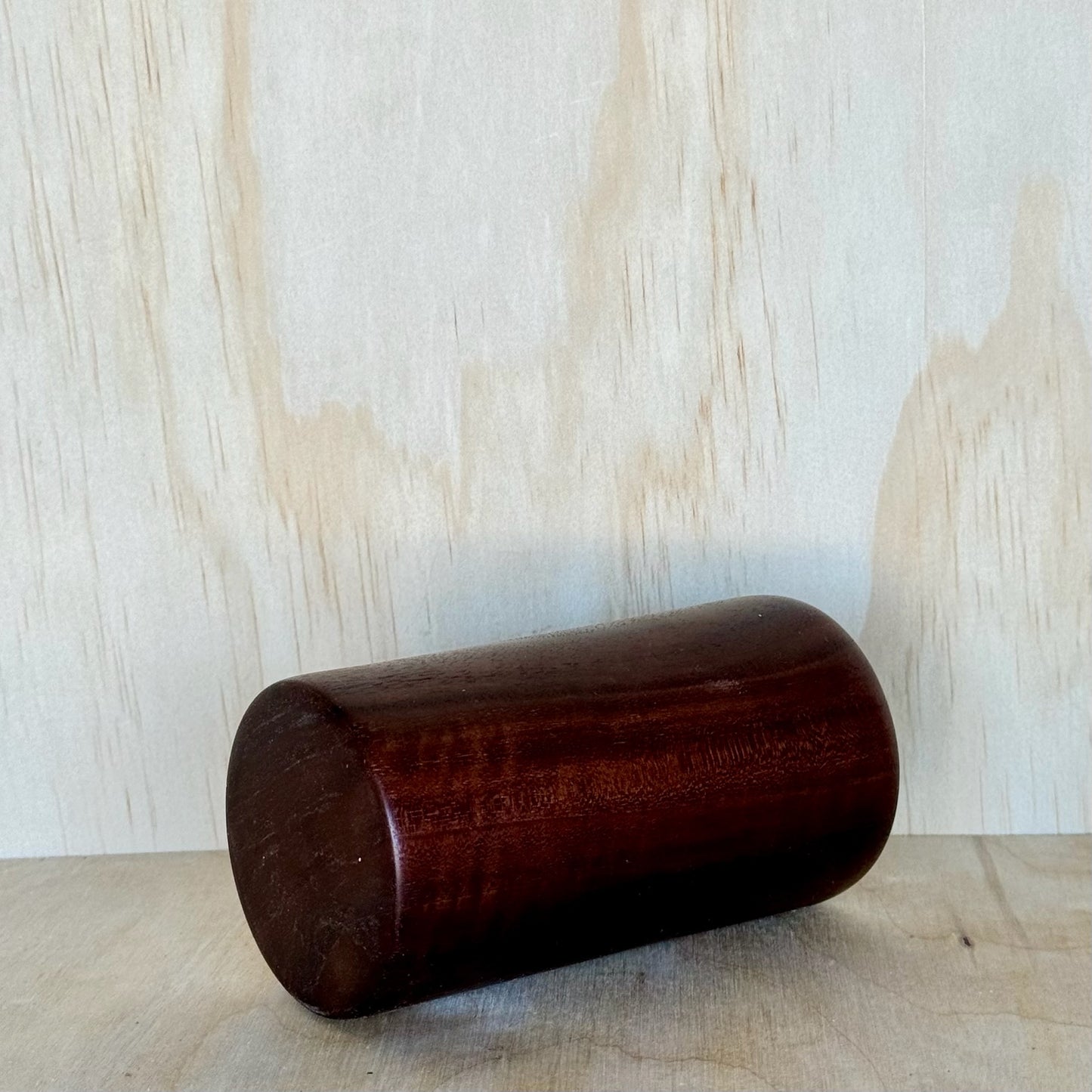Wooden tumbler on a wooden surface with a light wood panel background