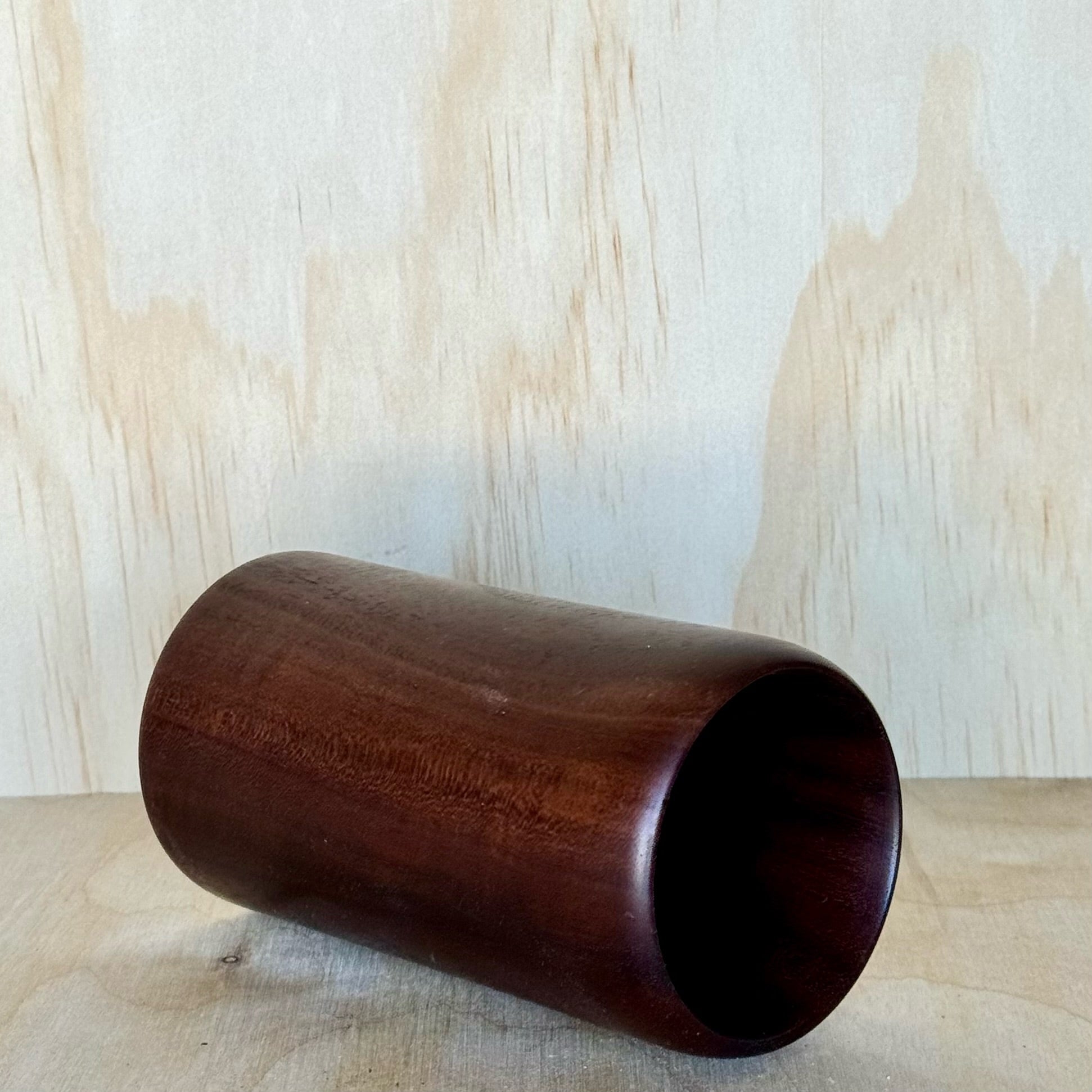 Wooden tumbler on a wooden surface with a light wood panel background