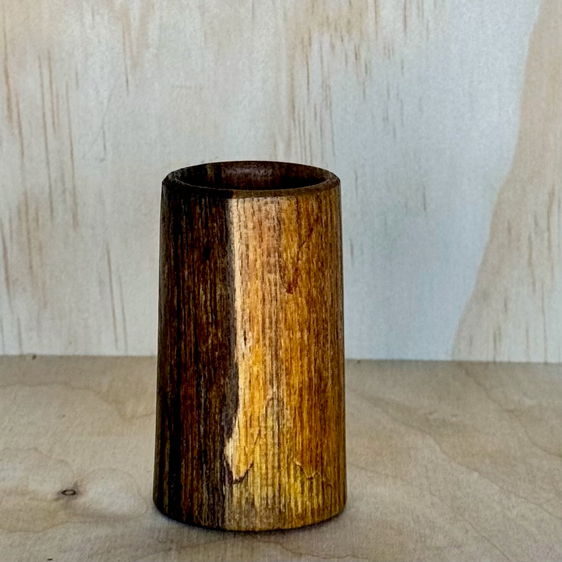 Wooden shot glass on a wooden surface with a light background