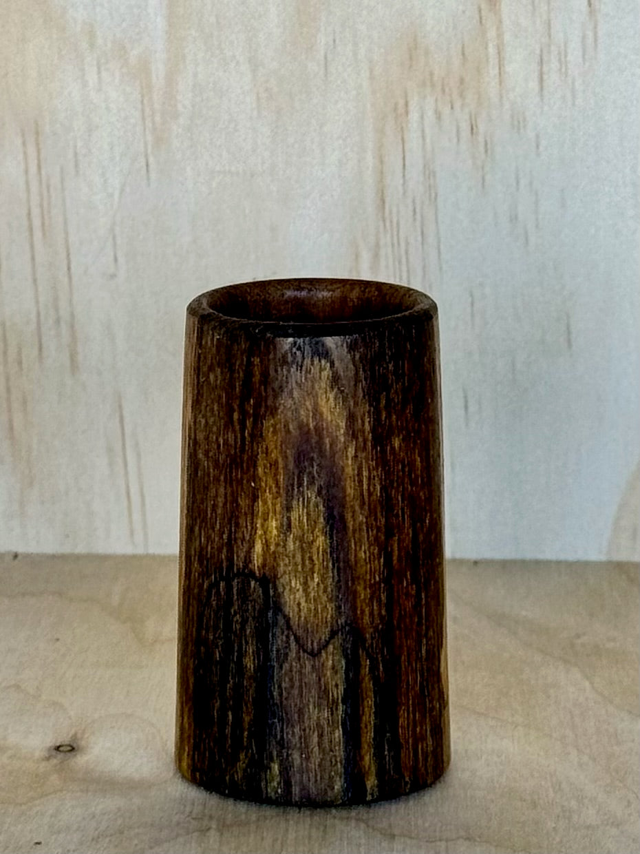 Wooden shot glass on a wooden surface with a light background