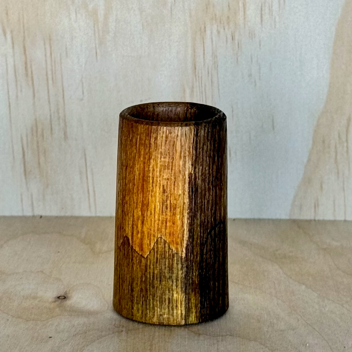 Wooden shot glass on a wooden surface with a light background