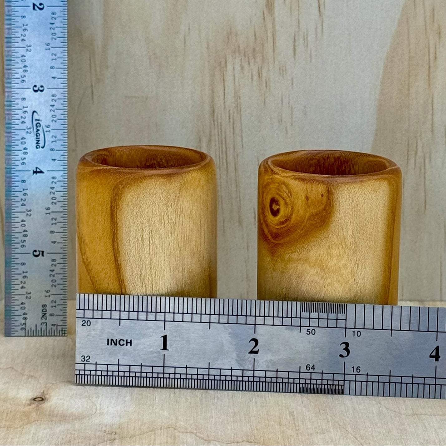 A pair of white mulberry shot glasses against a light background with rulers showing they are approximately 2-1/4 by 1-12 inches