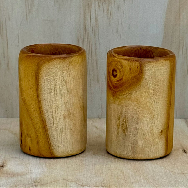A pair of white mulberry shot glasses against a light background
