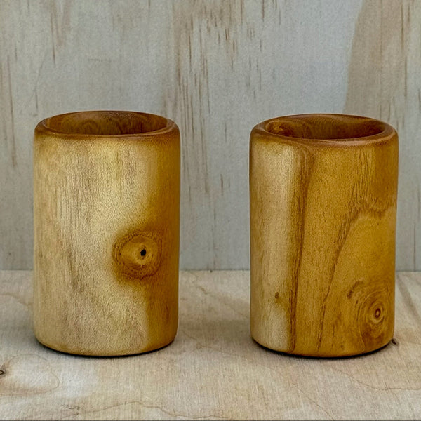 A pair of white mulberry shot glasses against a light background