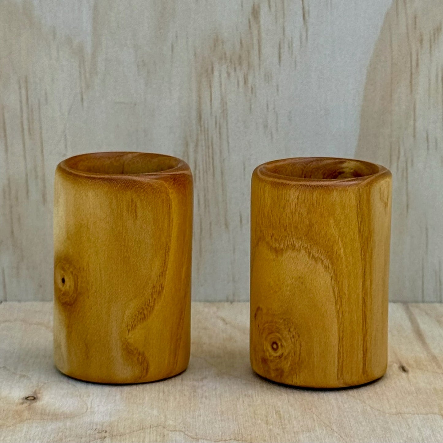 A pair of white mulberry shot glasses against a light background