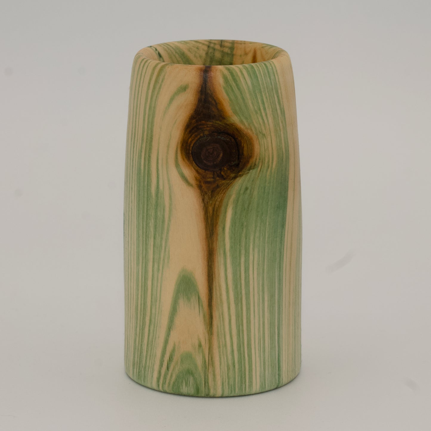 Wooden cup with green and brown marbled pattern on a wooden surface