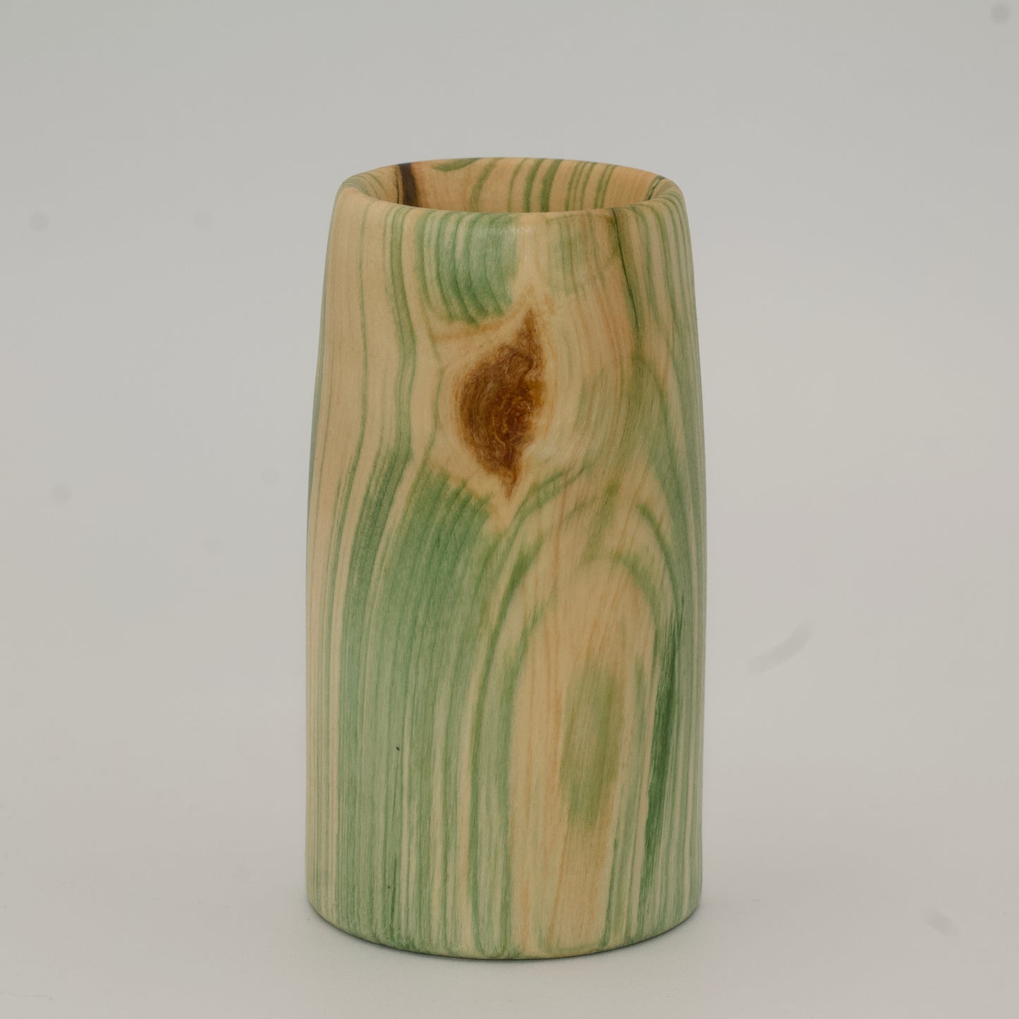 Wooden cup with green and brown marbled pattern on a wooden surface