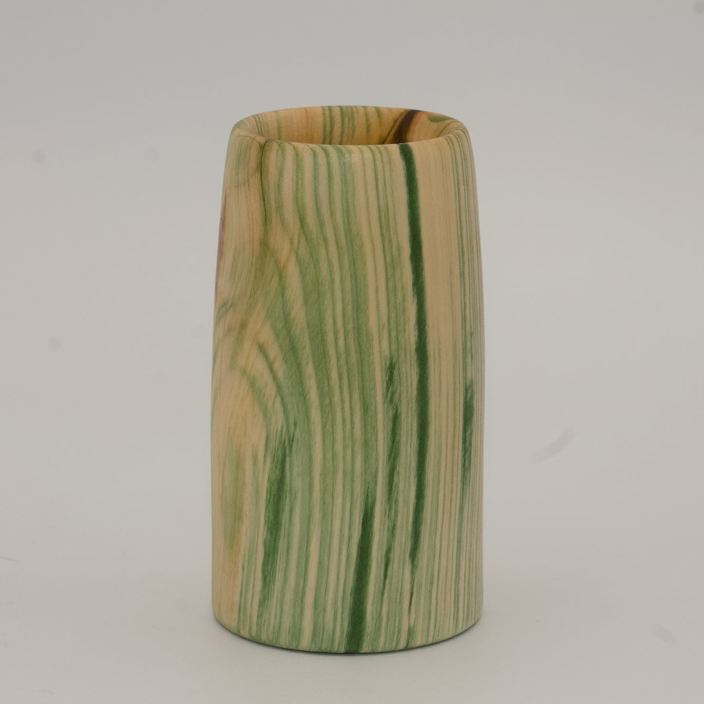 Wooden cup with green and brown marbled pattern on a wooden surface