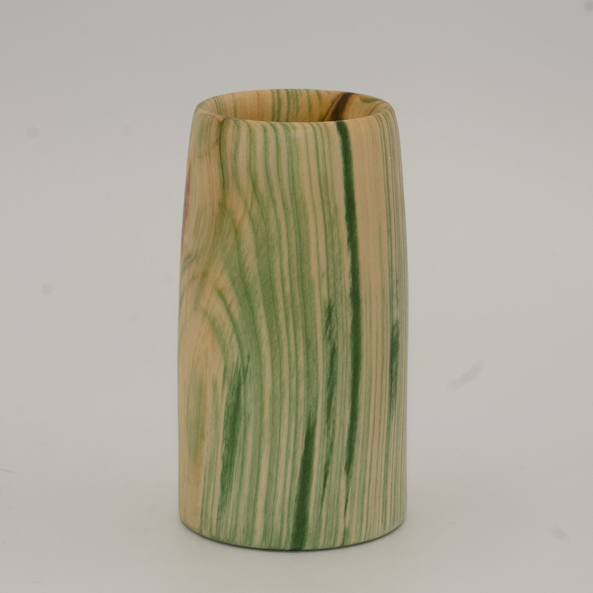 Wooden cup with green and brown marbled pattern on a wooden surface