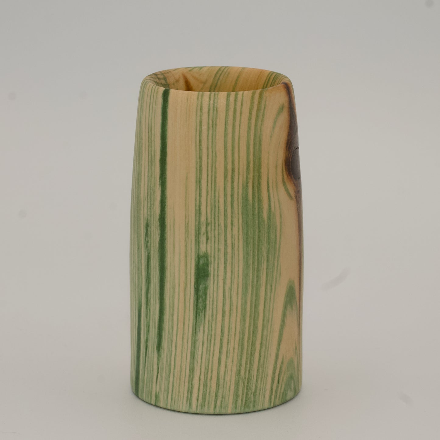 Wooden cup with green and brown marbled pattern on a wooden surface